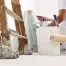 professional painter using a paint roller to paint an interior wall light blue