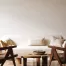 A modern neutral interior living room with wicker seating, custom shelving, and a white couch. A professionally painted cream wall is the background.