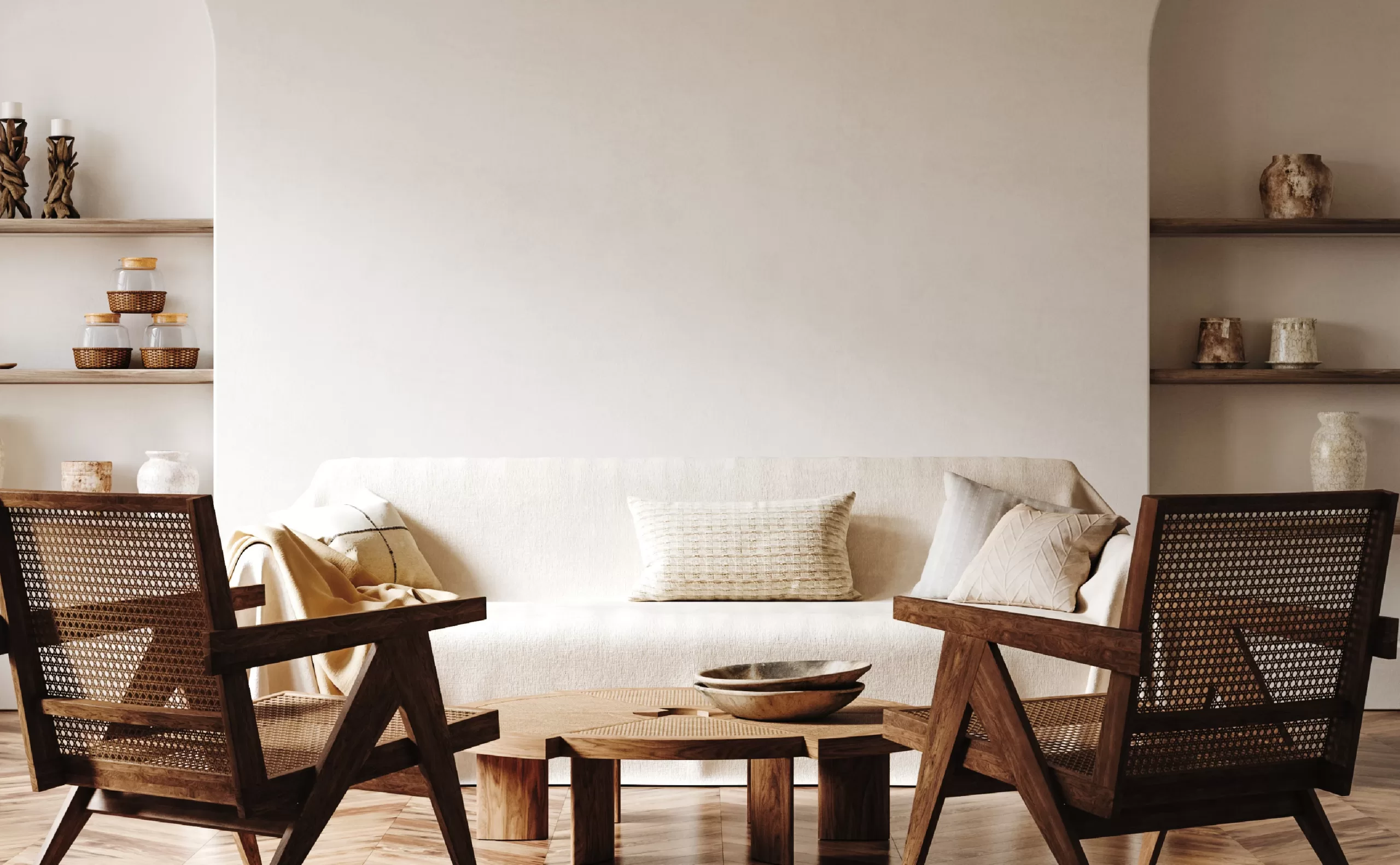 A modern neutral interior living room with wicker seating, custom shelving, and a white couch. A professionally painted cream wall is the background.