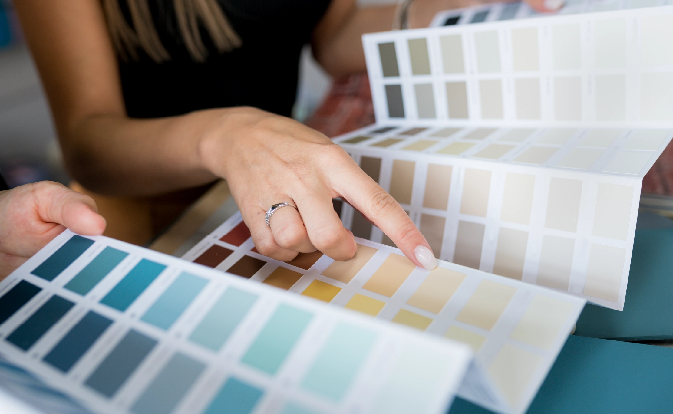 Close-up of two women choosing samples of wall paint. Interior designer consulting a client looking at a color swatch